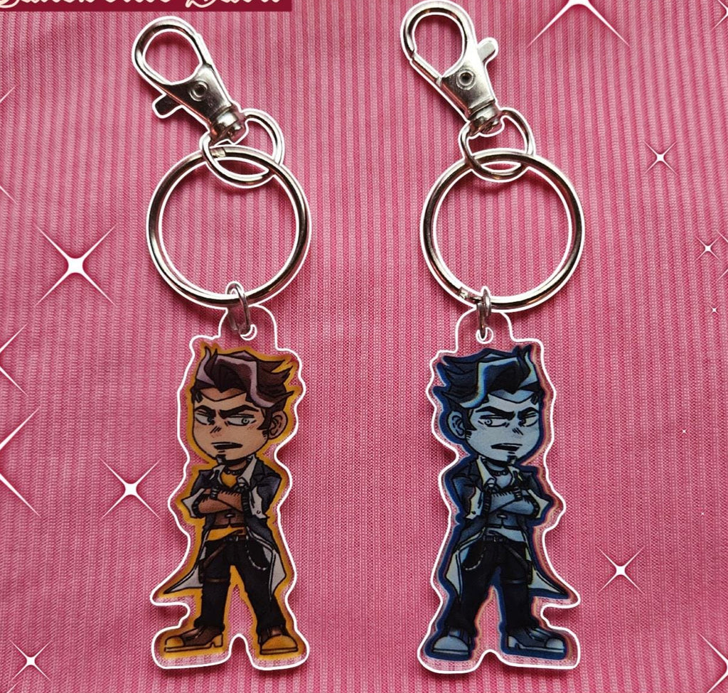 Two keychains with character figures on a pink background.